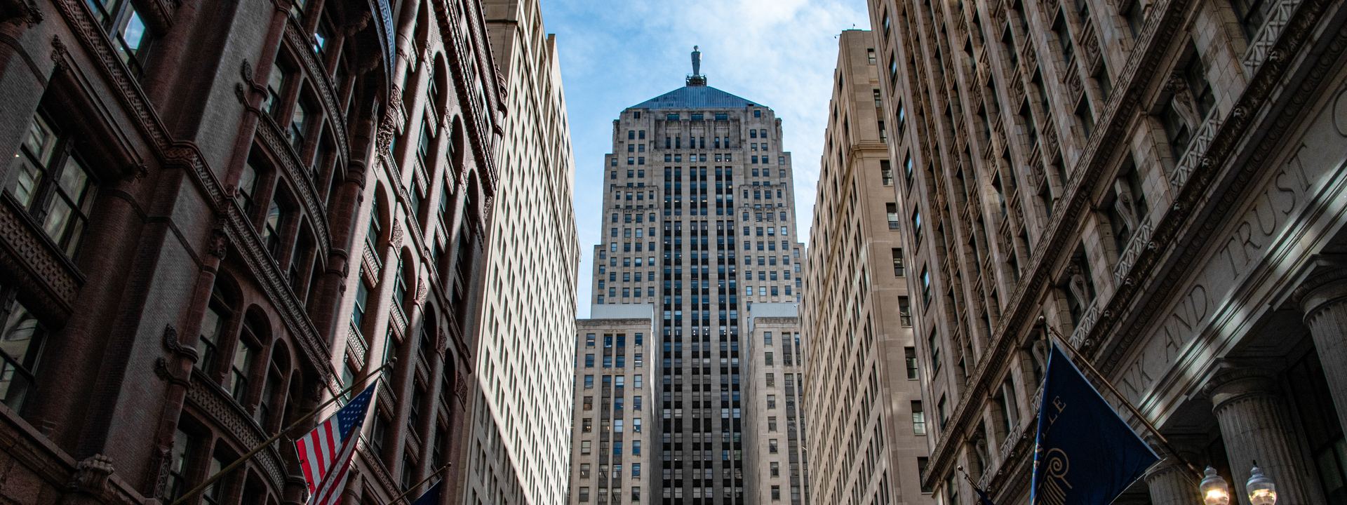 The Chicago Board of Trade tower seen from LaSalle Street, framed by bank buildings with flags along the block.