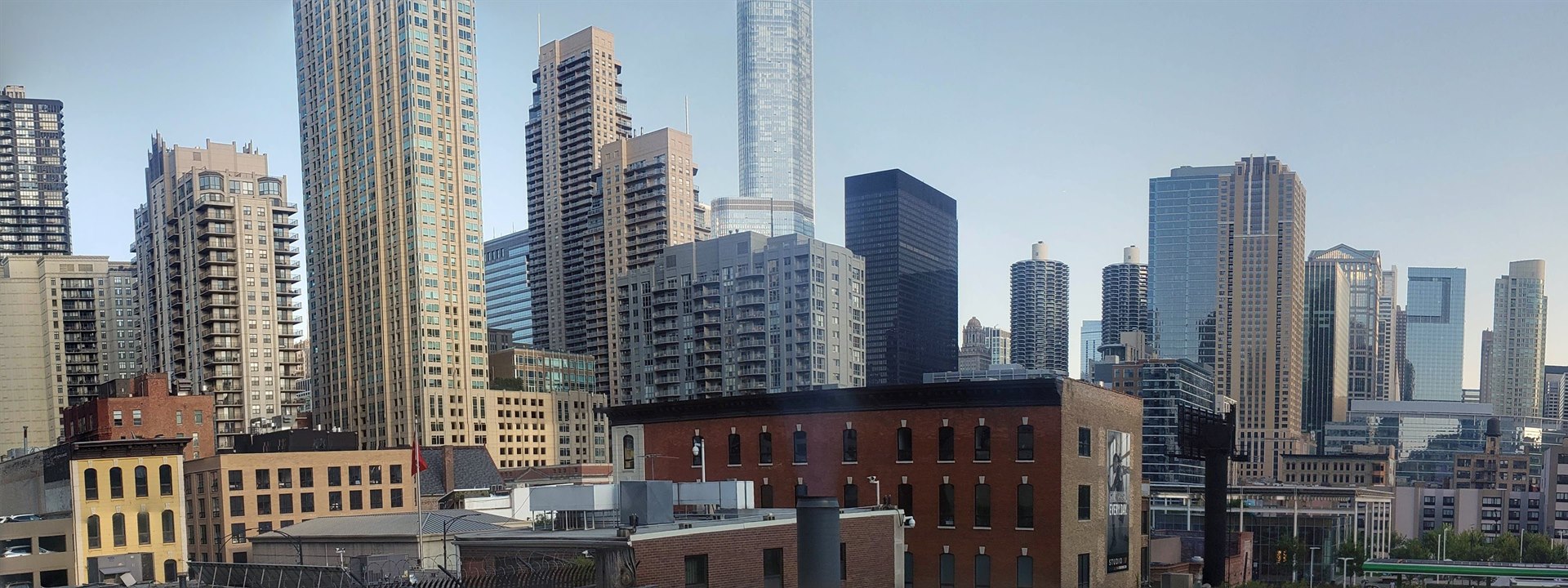 Low brick buildings layered against downtown Chicago glass towers in late afternoon light.